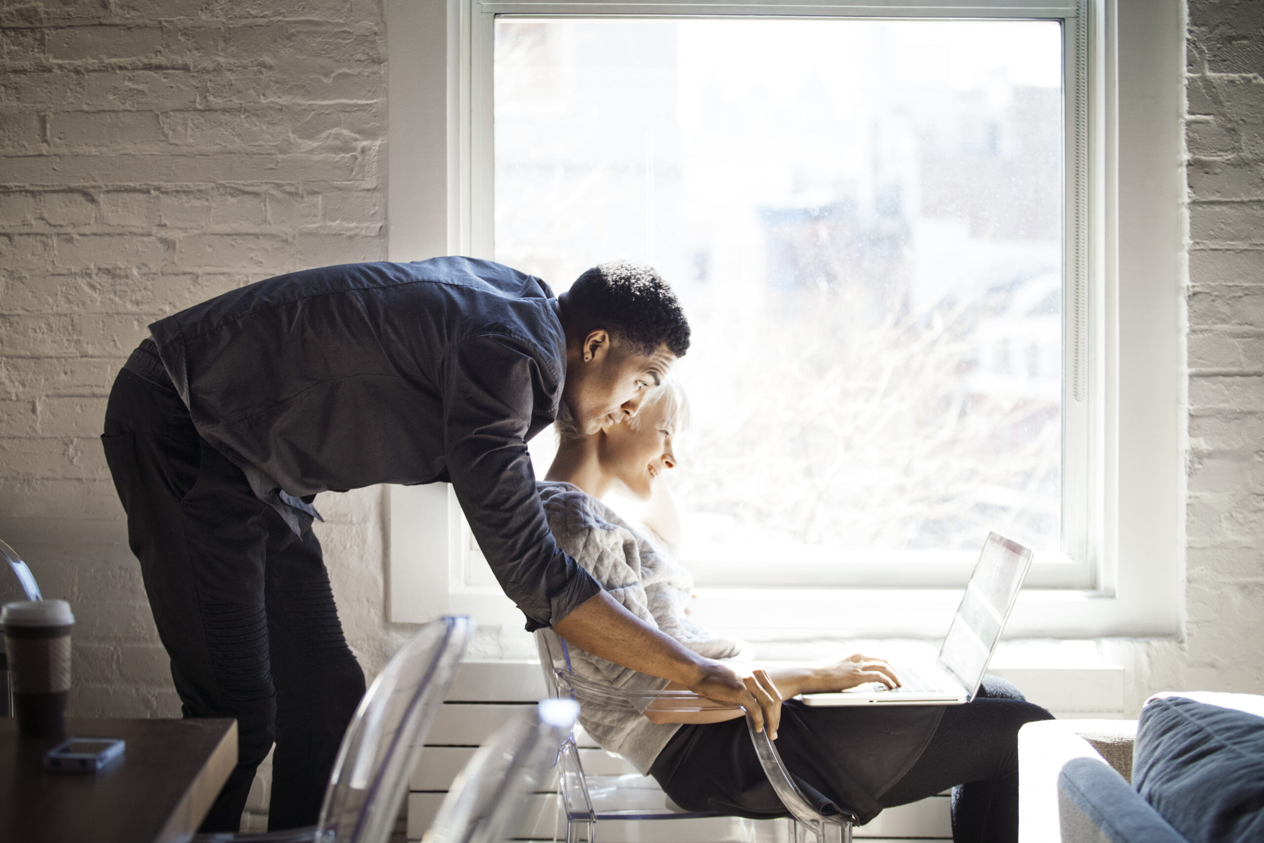 13. Side view of couple using laptop by window at home offset_376918