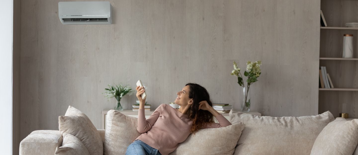 Smiling,Woman,Using,Air,Conditioner,Remote,Controller,,Relaxing,On,Comfortable