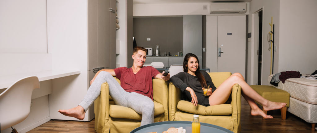 pria dan wanita bersantai di atas sofa sambil menonton tv
