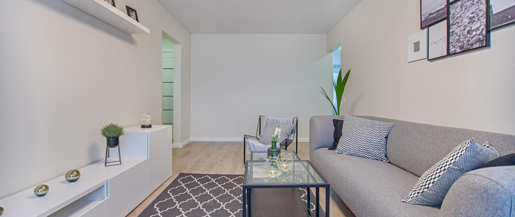 ruang tamu warna putih dengan karpet abu-abu gelap dan sofa abu-abu