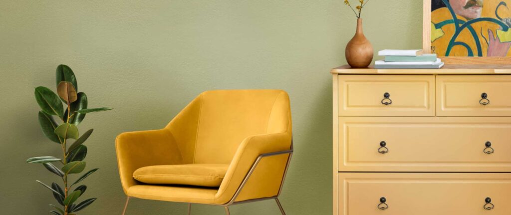 dinding warna sage dengan nakas warna kuning dan kursi kuning mustard