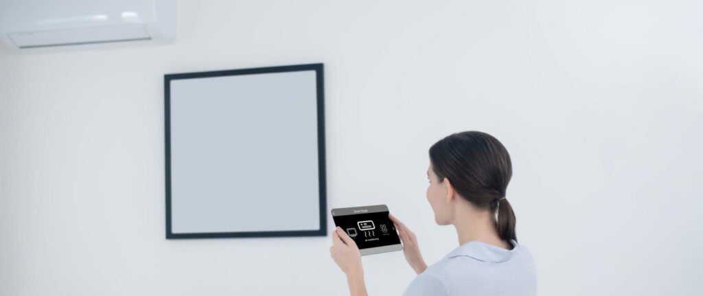 seorang wanita mengatur suhu ac dari tablet seorang wanita mengatur suhu ac dari tablet