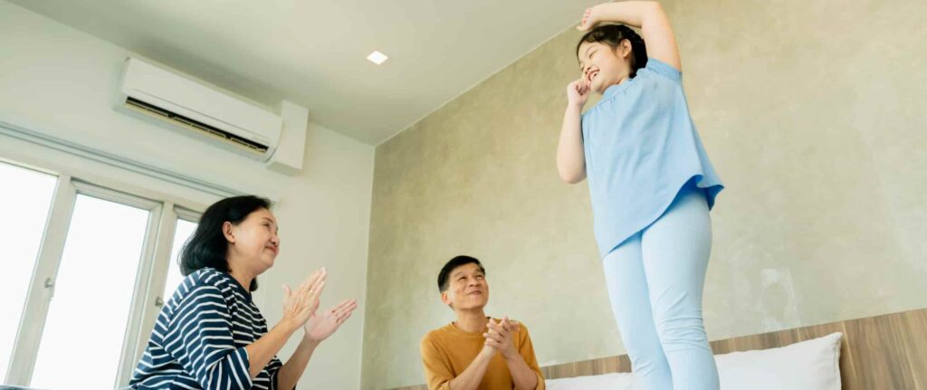 kakek dan nenek bertepuk tangan sambil tersenyum di atas kasur melihat cucu perempuannya kakek dan nenek bertepuk tangan sambil tersenyum di atas kasur melihat cucu perempuannya