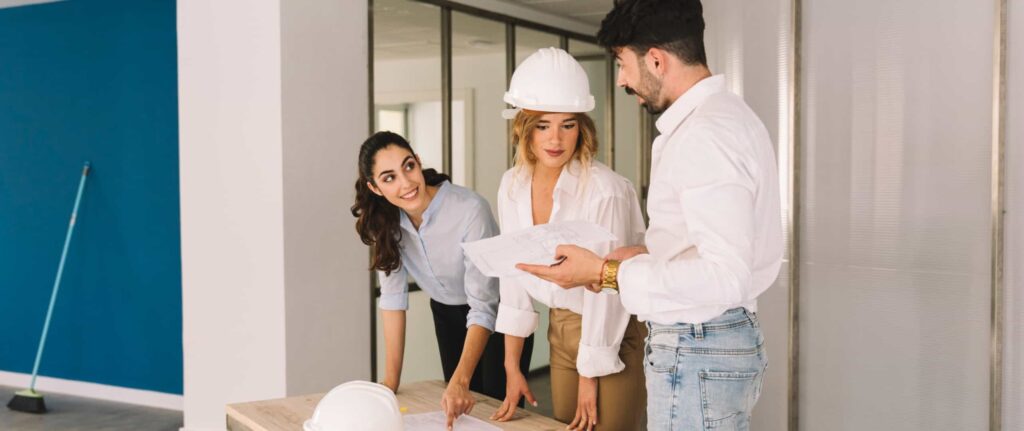 dua wanita dan satu pria sedang berdiskusi terkait proyek pembangunan