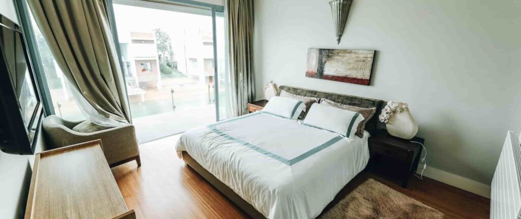 kamar tidur bernuansa hijau dan putih dengan jendela kaca besar