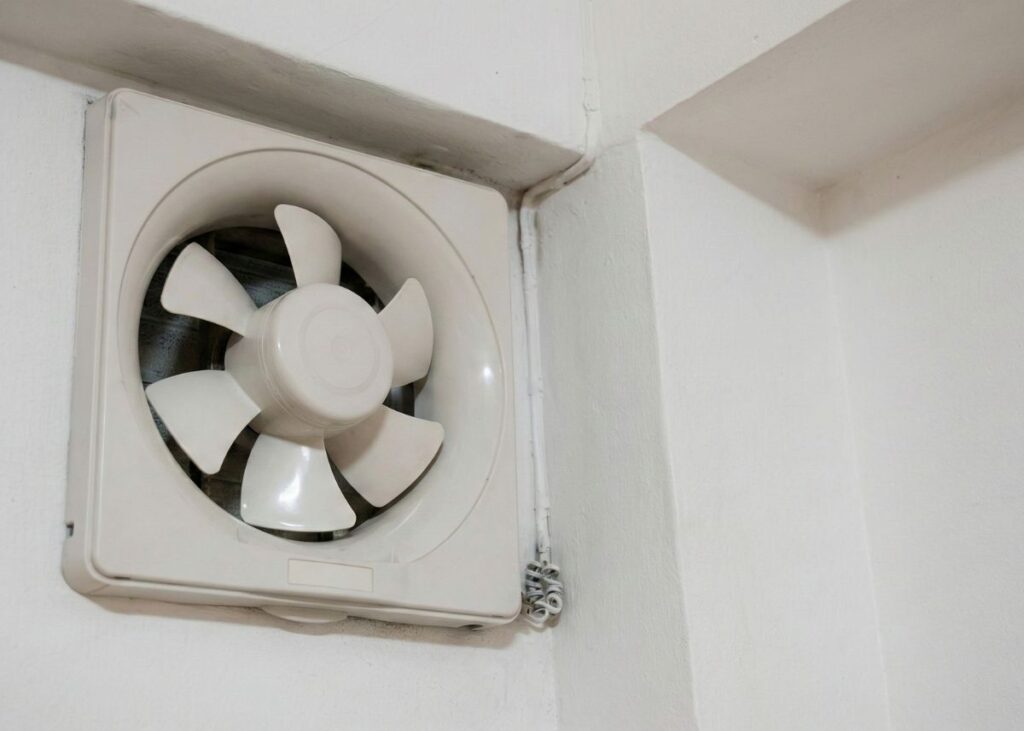 Kipas pembuangan udara plastik putih terpasang pada sudut dinding ruangan