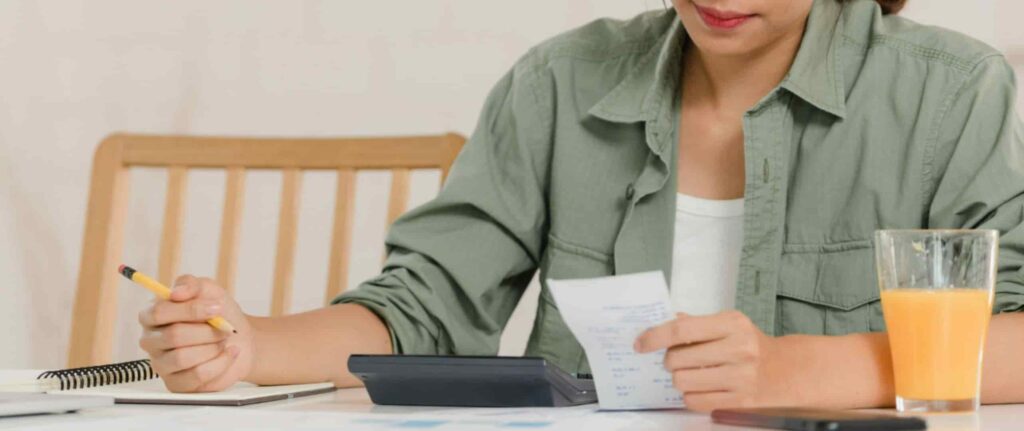 Wanita sedang menghitung dengan kalkulator