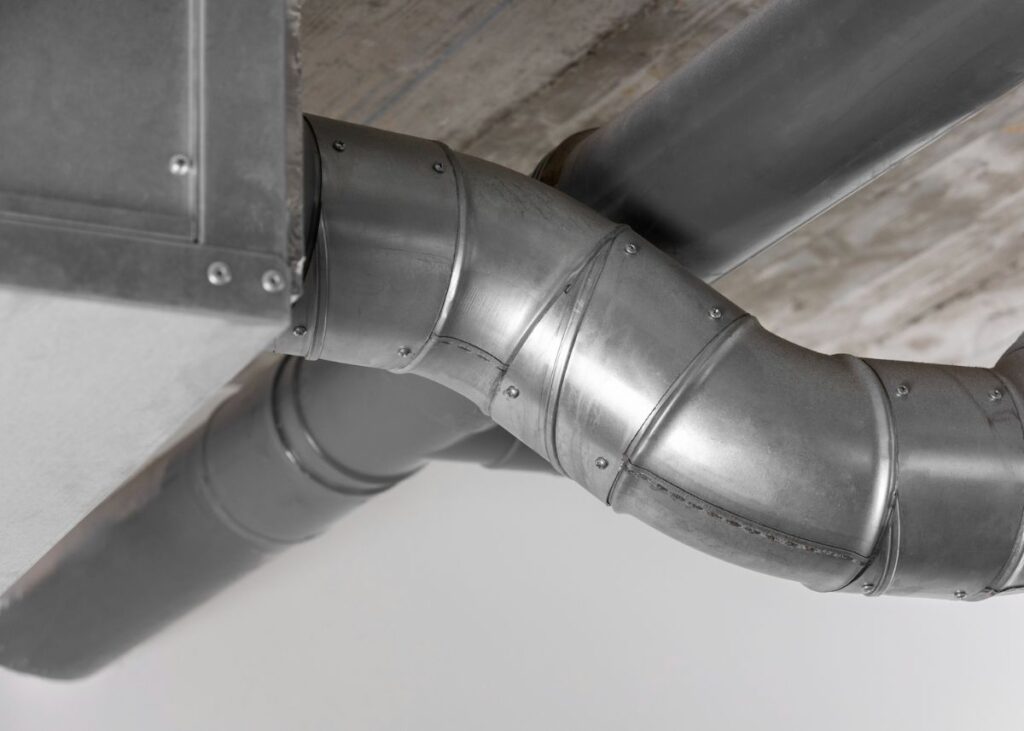 Pipa saluran udara logam besar yang saling terhubung di bawah langit-langit beton